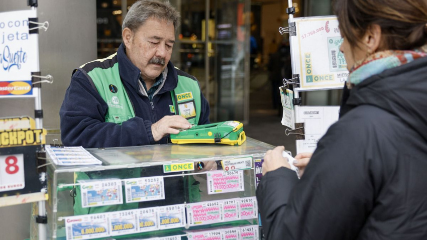 Un vendedor de la ONCE atendiendo a unos clientes