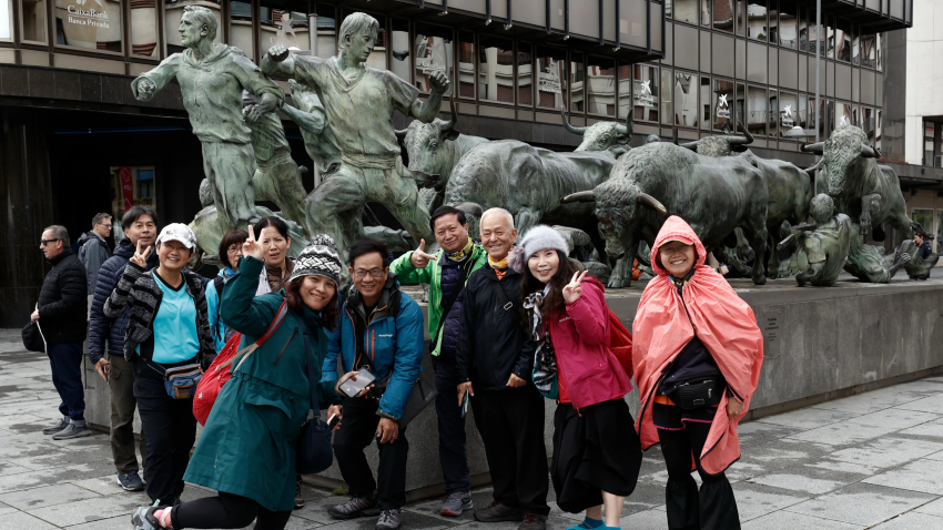Un grupo de turistas posa en Pamplona junto al Monumento al Encierro.