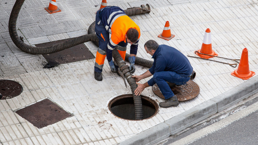 Imagen de recurso de dos hombres limpiando una alcantarilla
