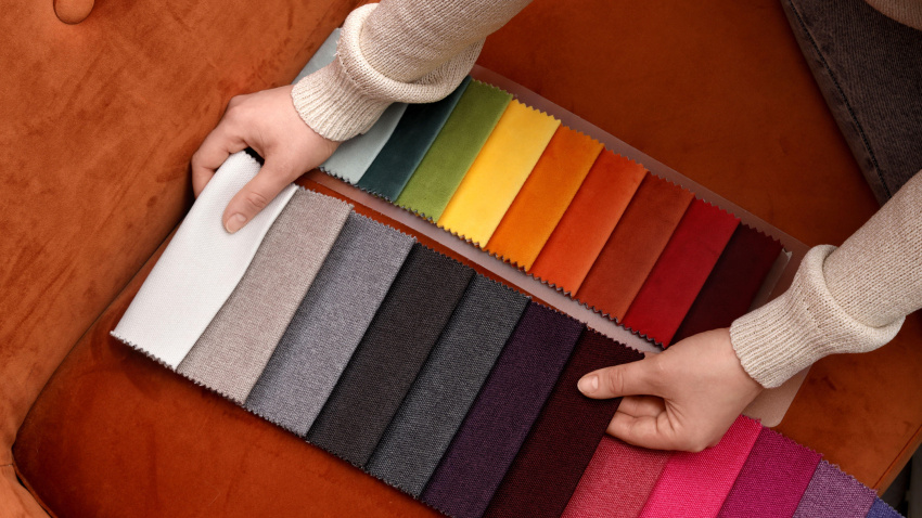 Mujer con muestras de tela en un sofá rojo en una tienda de muebles.