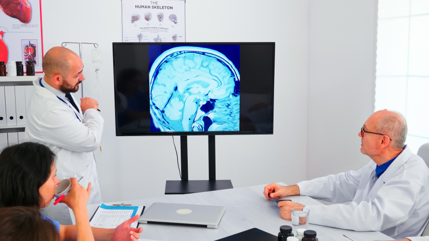 Physicians talking with specialist doctors during medical conference. Expert doctor using modern technology, pointing on digital radiography brainstorming with medicine staff for expertise.