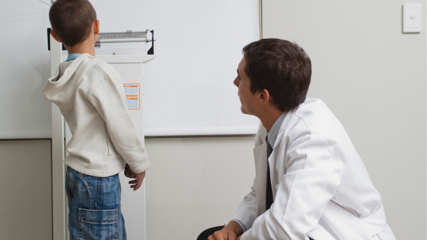 Un pediatra toma la altura a un niño, imagen de recurso