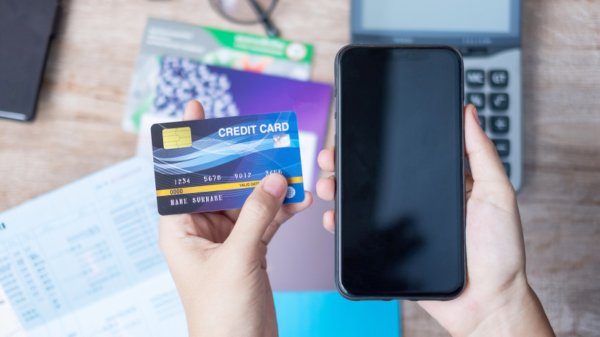Woman holding credit card and using smartphone for online payment at home office. business, lifestyle, technology, ecommerce, digital banking and online shopping concept