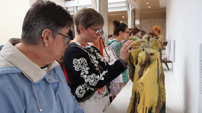 Una afiliada a la ONCE conoce, al tacto, una de las obras expuestas