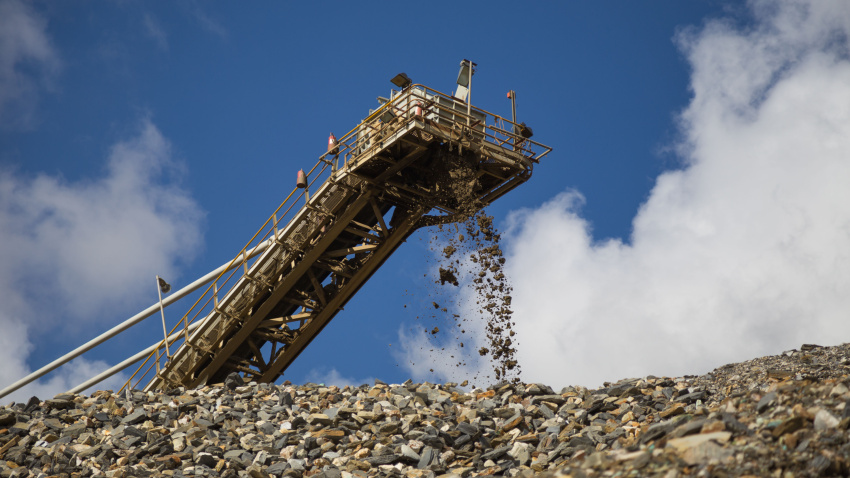 En una gran mina de cobre y oro en África, el material cae de una cinta transportadora sobre un montón de material almacenado.