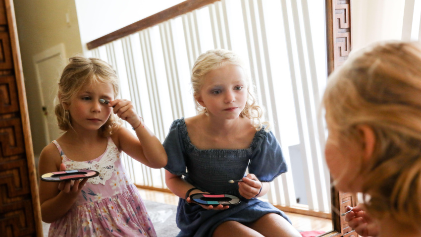 Niñas pequeñas maquillándose juntas frente al espejo