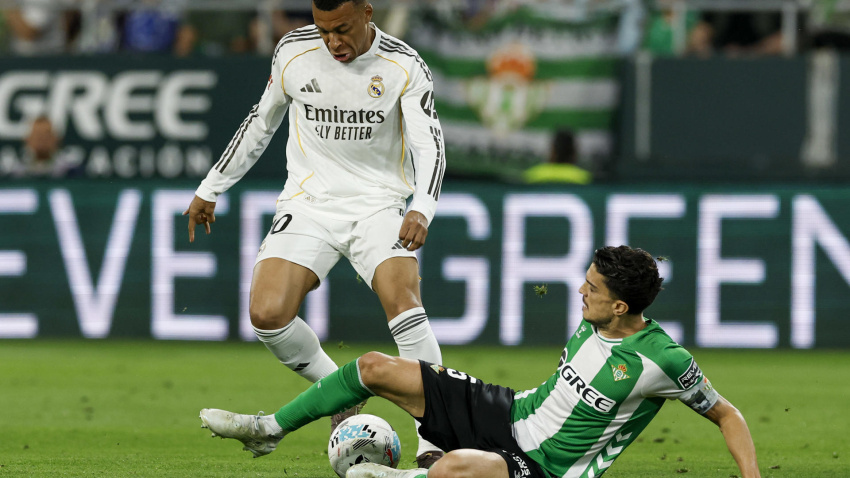 El delantero francés del Real Madrid, Kylian Mbappé (i), disputa el balón ante el defensa del Betis, Marc Bartra, durante el encuentro correspondiente a la jornada 32 de Laliga EA Sports que disputan este viernes Betis y Real Madrid en el estadio de La Cartuja, en Sevilla