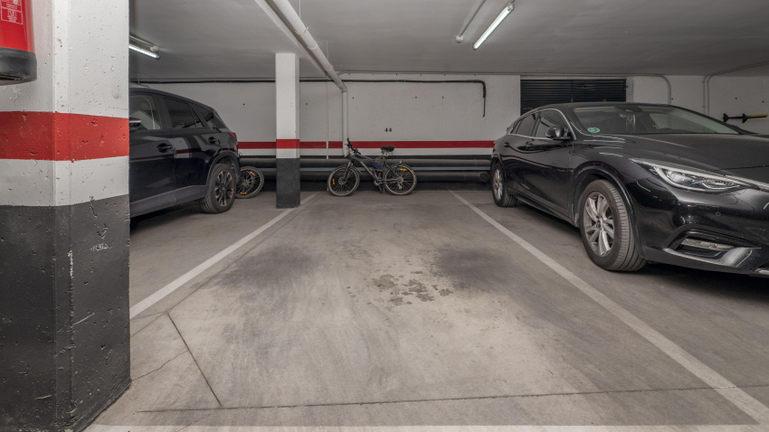 Un garaje subterráneo de un edificio de apartamentos residenciales urbanos con algunos espacios ocupados.