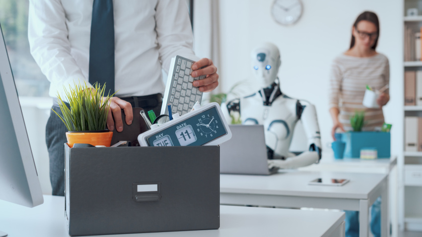 Dismissed business people packing their belongings and leaving the office, a robot is sitting at the desk and working: the impact of AI on jobs