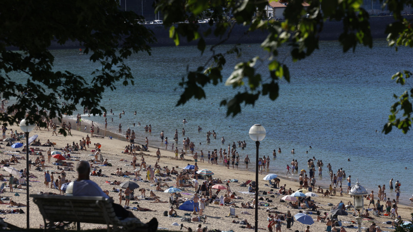 Un hombre observa desde la sombra la playa de Ondarreta de San Sebastián