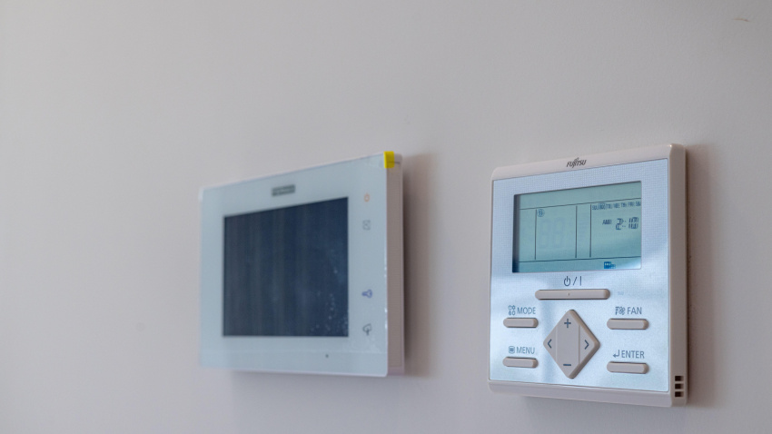 Paneles de control de temperatura y aire acondicionado modernos e inteligentes instalados en una pared blanca impoluta dentro de una villa de lujo.