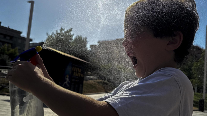 Un niño se refresca en un parque por la ola de calor