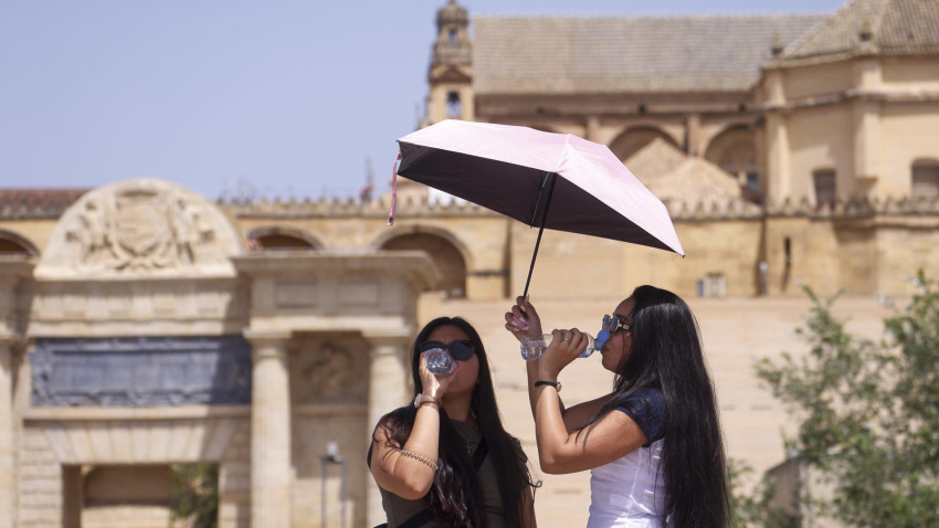 Varias turistas se protegen con paraguas mientras se refrescan ante la ola de calor