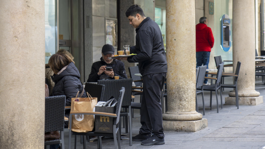 Un camarero sirve un café en la terraza de una cafetería en Teruel
