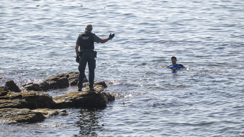 Un guardia civil alerta a un migrante que nada en el mar ante la frontera de El Tarajal