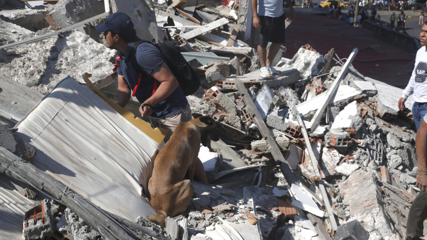 Personas caminan sobre los escombros de un edificio colapsado este lunes, en Cali (Colombia). Al menos 20 edificios sufrieron graves daños por consecuencia del terremoto de magnitud 7,4 que sacudió la mayor parte del país, con epicentro en la zona del Pacífico. EFE/ Ernesto Guzmán