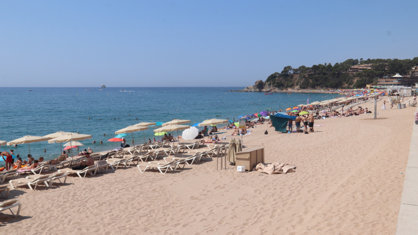 La playa de Lloret de Mar llena de bañistas, tumbonas y sombrillas