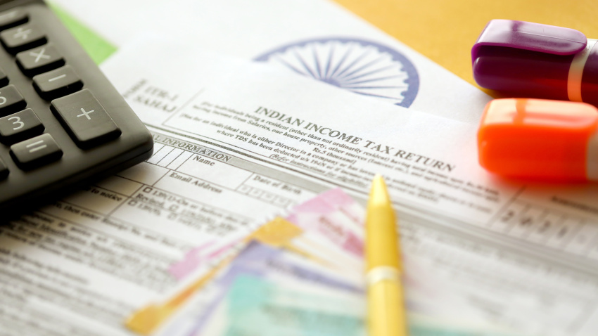 Indian income tax return blank form with pen and indian rupees bills on indian country flag close up. Annual tax report concept