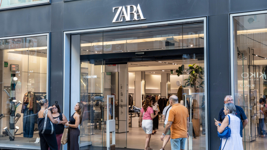 Tienda de ropa y accesorios Zara en el centro de Barcelona; clientes frente al establecimiento, entre ellos una mujer fumando un cigarrillo.