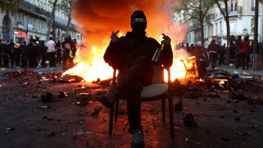 un-joven-manifestante-frances-posa-ante-una-barricada-en-llamas-realizando-un-doble-corte-de-manga-botella-en-mano