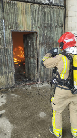 Un bombero trabaja en la extinción del incendio en la nave industrial