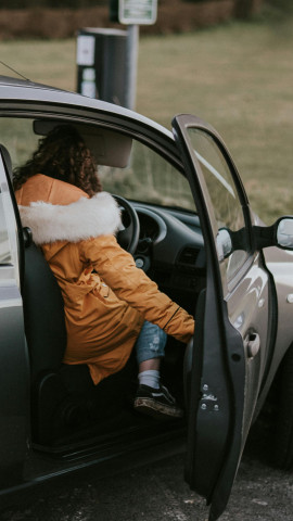 Una chica entra al coche con el chaquetón puesto