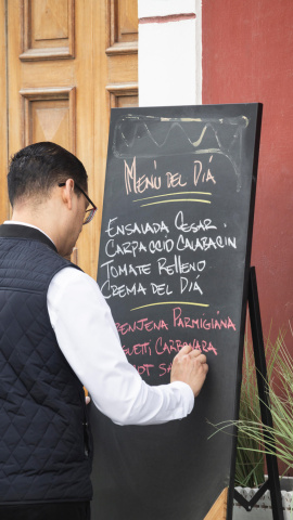 T1F4EM Waiter writing Menu del dia, [menu of the day] on blackboard outside restaurant in Vegueta, Las Palmas, Gran Canaria, Canary Islands, Spain
