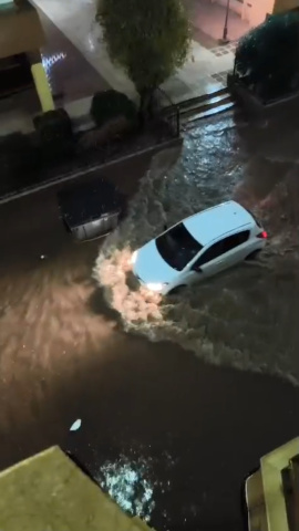 Un coche atraviesa la calle Carlos III de Águilas completamente anegada, tras la lluvia del martes de madrugada