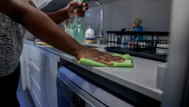 Una empleada de hogar limpia la encimera de la cocina