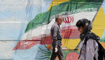 Un hombre pasea junto a un moral de la bandera de Irán en Teherán