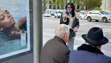 Pilar Cisneros habla con pasajeros en una de las marquesinas de la Puerta de Alcalá