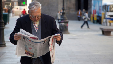 Un anciano lee el periódico en las calles del antiguo Barrio Gótico de Barcelona, ​​España