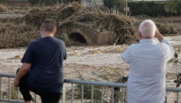 Varios vecinos contemplan el puente arrastrado por el agua en Ribarroja del Turia (Valencia), tras las intensas lluvias de la fuerte dana que afecta especialmente el sur y el este de la península ibérica, este miércoles