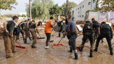 Voluntarios y fuerzas de seguridad trabajan para despejar una calle de Paiporta