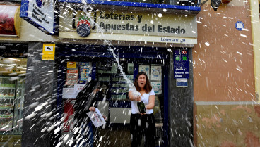 Una mujer salpica vino durante las celebraciones. Celebraciones de la lotería de Navidad 2018 de un cuarto premio del sorteo, Se ha vendido el número de Lotería 67774 en la Administración número 29 del Barrio de Santa Eulalia Dotado con 200.000 euros en cada serie