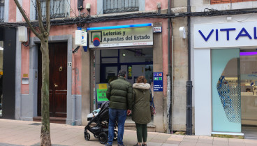 Una pareja frente a un establecimiento de Loterías y Apuestas del Estado durante los últimos preparativos de la Lotería de Navidad, el 21 de diciembre de 2023, en Oviedo, España