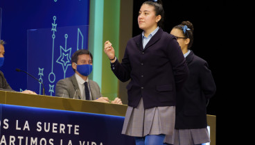 Yanisse Alexandra, una de las niñas de la residencia San Ildefonso, posa minutos después de cantar el primer premio 86.148, durante la celebración del Sorteo Extraordinario de Lotería de Navidad 2021 en el Teatro Real de Madrid