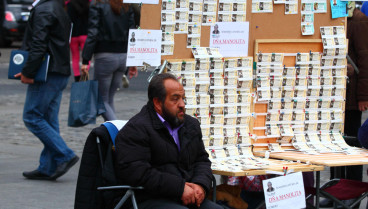 Un hombre se sienta junto a su puesto de venta de billetes de la Lotería de Navidad en la Plaza Puerta del Sol, en el centro de Madrid