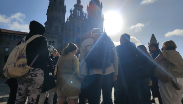 Un grupo de turistas atiende a las explicaciones de la guía en el Obradoiro