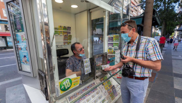 Un hombre compra un cupón en un puesto de la ONCE