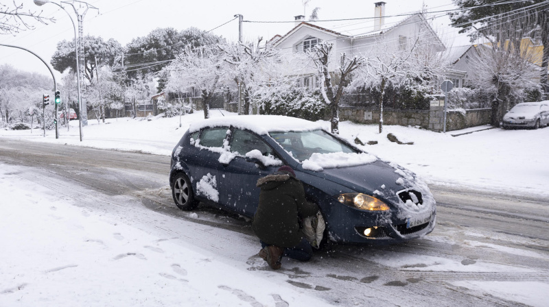 Un hombre pone las fundas a las ruedas de su coche para poder circular en una carretera en Alpedrete, este miércoles, en el que la borrasca Kristin deja nieve en la región de Madrid.