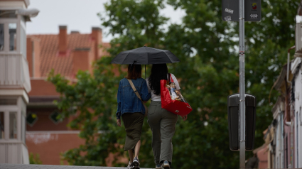 Dos mujeres se protegen de la lluvia con un paraguas en Madrid