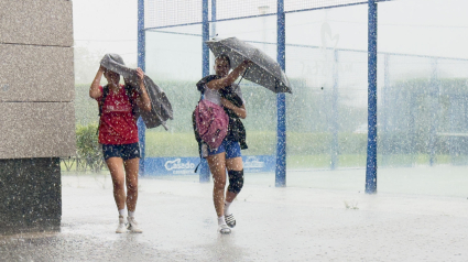 Unas jóvenes corren para protegerse de la tormenta en Logroño