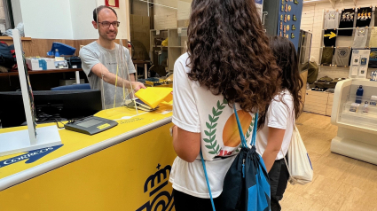 Un empleado entrega bolsas a peregrinos en una oficina de Correos de Lugo