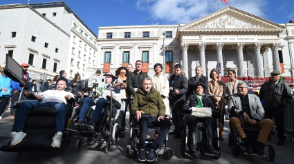 En la primera fila, el exfutbolista y portavoz de ConELA, Juan Carlos Unzué (c) y en la segunda fila, el presidente de ConELA, Fernando Martín (c) y la diputada de Sumar, Tesh Sidi (1d), acuden junto a otros miembros de la Confederación Nacional de Asociaciones de la ELA, ConELA, a la presentación de la nueva Proposición de Ley, elaborada por las entidades de ELA, en la plaza de las Cortes, a 30 de octubre de 2023, en Madrid