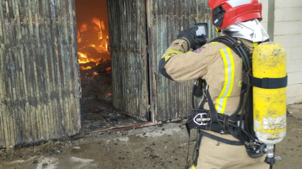 Un bombero trabaja en la extinción del incendio en la nave industrial