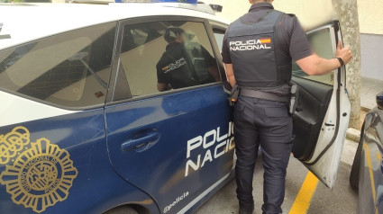 Un agente de la Policía Nacional junto a un vehículo policial