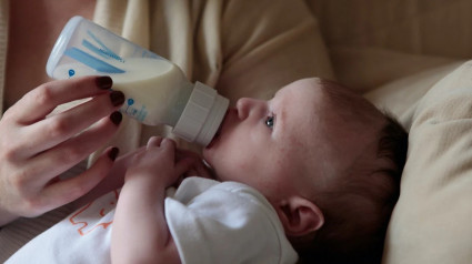 Un bebé toma leche de un biberón