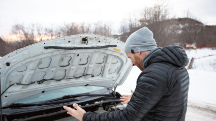 Hombre cerca del coche averiado en invierno