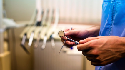 Dentista sosteniendo un espejo dental y una sonda en primer plano